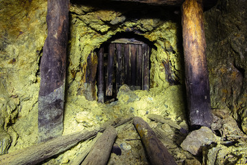 Underground abandoned ore mine shaft tunnel gallery passage with wooden timbering