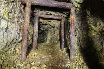 Underground abandoned ore mine shaft tunnel gallery passage with wooden timbering