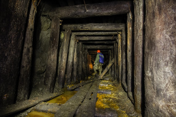 Underground abandoned ore mine shaft tunnel gallery passage with wooden timbering