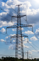 Electricity pylon silhouetted against blue sky background. High voltage tower