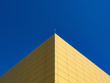 Fototapeta  - A fragment of the building is yellow in the background of the sky at noon.