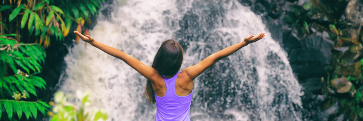 Wall Mural - Freedom zen happy girl with open arms meditating yoga at nature waterfall banner panoramic. Hawaii travel woman at Canyon Trail Waipoo Falls in Waimea, Kauai island, USA.