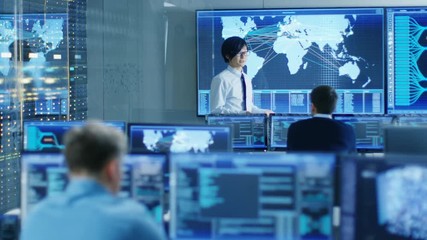 Fototapete - In the System Control Room Manager Holds a Briefing for His Staff Members. They're Work in Data Center and are Surrounded by Multiple Screens Showing Maps, Logistics Data. 