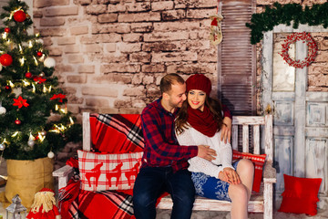 Nice couple sitting on the bench in a loft decorated for christm