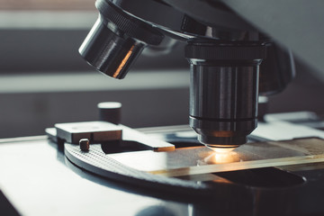 Wall Mural - close-up shot of microscope with metal lens at laboratory.