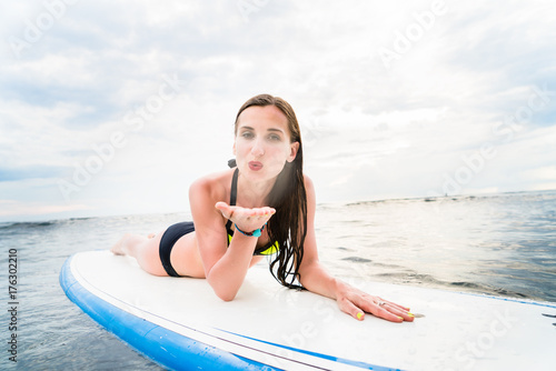 Plakat Kobieta surfer paddling podatne na deska surfingowa na otwartym morzu do surfowania
