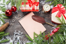 Christmas Fir Trees In Snow With Cone, Vintage Clock, Christmas Balls, Giftboxes On A Dark Wooden Board. Blank Notebook With Qull Feather Pen For Your Text