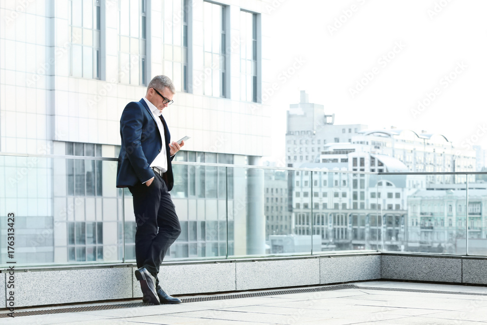 Elegant businessman using mobile phone outdoors