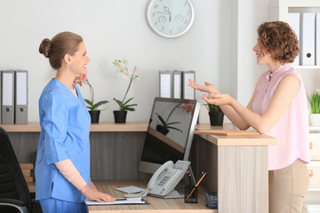 Young female receptionist with client in hospital