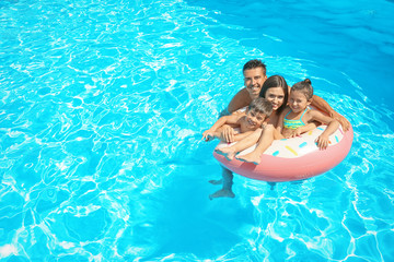 Poster - Happy family with inflatable ring relaxing in swimming pool