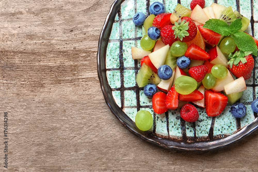 Plate with fruit salad on wooden table