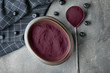 Acai powder in metal bowl and spoon on grey background
