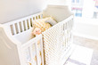 Closeup of bright yellow baby crib in nursery room with toys and pillow in model staging home, apartment or house