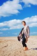 © raisondtre - Fashion shooting at sandy beach. Beautiful slender self-confident model posing in elegant coat in a bright Sunny day on a background of blue cloudy sky.