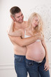 © olharozova - Beautiful pregnant couple in love on the background. Hands of husband on the tummy of his pregnant wife. Young man tenderly stroked pregnant belly of his wife. Husband kissing pregnant belly.