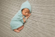 Tiny baby in mint dress sleeps on the woolen blanket
