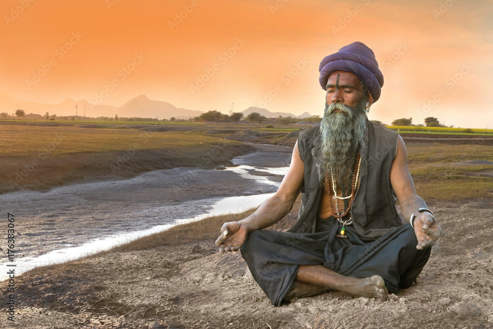 Sadhu meditation near river - obrazy, fototapety, plakaty 
