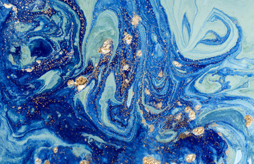 Marbled blue abstract background with golden sequins. Liquid marble ink pattern.