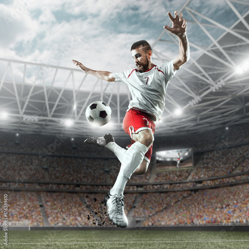Zdjęcie XXL Piłkarz wykonuje grę akcji i bije piłkę na profesjonalnym stadionie. Gracz nosi niemarkowy mundur sportowy.
