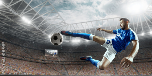 Plakat Piłkarz wykonuje grę akcji i bije piłkę na profesjonalnym stadionie. Gracz nosi niemarkowy mundur sportowy.