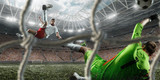Fototapeta Sport - Soccer player scores the ball into the goal on professional stadium. The goalkeeper protects the football gate. Players wears unbranded sport uniform. View through the football gate.