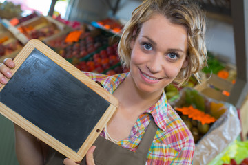 smiling female staff holding board in supermarket