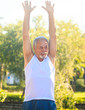 © SlavaStock - Grey Bearded Old Man in Vest Lifts Hands up Smiles in Park