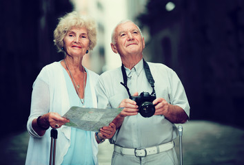 Wall Mural - Senior woman and man traveling together looking for destination with city map