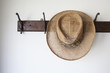 © Lisa MacIntosh/Stocksy - Old straw hat on antique coat rack hook