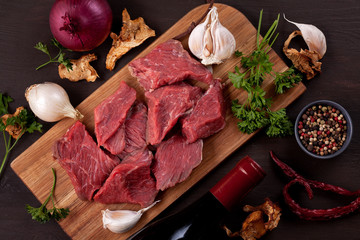 Raw fresh meat, bottle of wine and seasonal autumn organic vegetables on wooden board ready for cooking