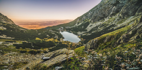 Wall Mural - Mountain Lake at Sunset with Flowers and Hiking Trail in Foreground. Velicke Tarn, High Tatras, Slovakia.