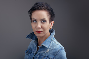 Studio portrait of beautiful cool edgy middle aged white caucasian brunette woman with blue eyes. Aged European sexy model with dark short hair looking in camera.