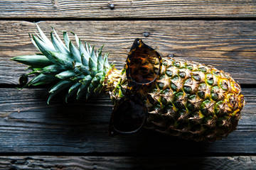 Wall Mural - Ripe pineapple with sunglasses on a white wooden table. Fruit, nature, food