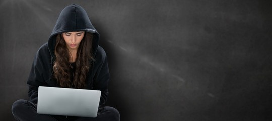 Wall Mural - Composite image of young female hacker using laptop while