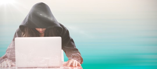 Wall Mural - Composite image of female hacker sitting by laptop on table 