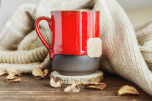 Red Mug Of Herbal Tea, Beige Cozy Knitted Sweater And Dry Leaves On  The Wooden Background. Delicious Cold Weather Beverage For Fall Times. Stay At Home Concept.