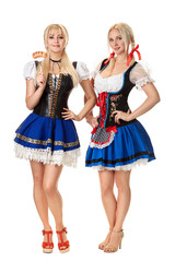 Wall Mural - Full length portrait of a two blond womans with traditional costume holding beer glasses isolated on white background.