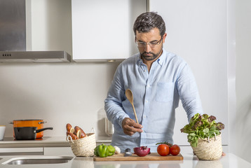 Wall Mural - arab man preparing food in his urban apartment