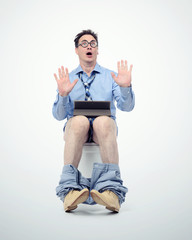 Funny man in tie with tablet pc sitting on the toilet.