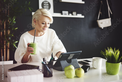 Zdjęcie XXL Kobieta z smoothie używać cyfrową pastylkę przy jej biurkiem