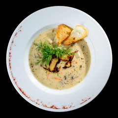 Sticker - Tasty mushroom cream soup with parsley and spices in a white plate served with toast bread, isolated on black background. Top view, flat, overhead. Autumn menu in an Italian restaurant