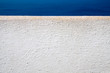white painted wall detail on the background of deep blue sea, Santorini Greece.