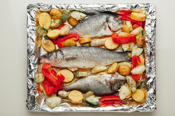 raw fish and vegetables on the baking tray