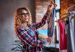 © Fxquadro - A woman chooses fashionable clothes on the coat rack.