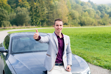 Young, happy, business man in the car. Man in a suits standing by the expensive, sport car. Successful young man. 