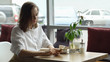 © lenblr - a girl uses a cell phone sitting in a cafe. a young woman sends a message with mobile phone and drinking coffee
