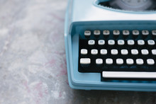 Blue Retro Typewriter Against A Concrete Background