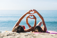 Women Making Heart Shape With Their Hands On The Beach