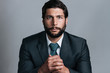 © Leander Nardin/Stocksy - studio portrait of full bearded well dressed young business man looking in the camera