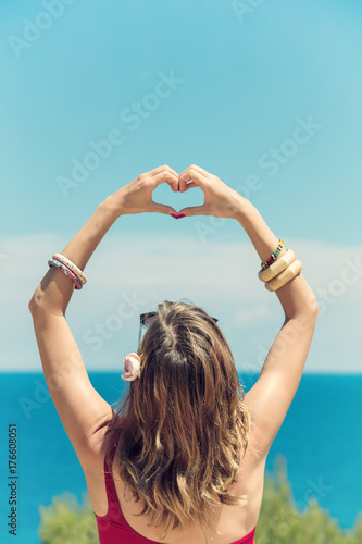 Zdjęcie XXL Dziewczyna trzyma kształt serca na brzegu oceanu / morza.